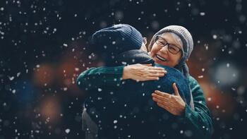Eldre par gir hverandre en klem ute mens det snør
